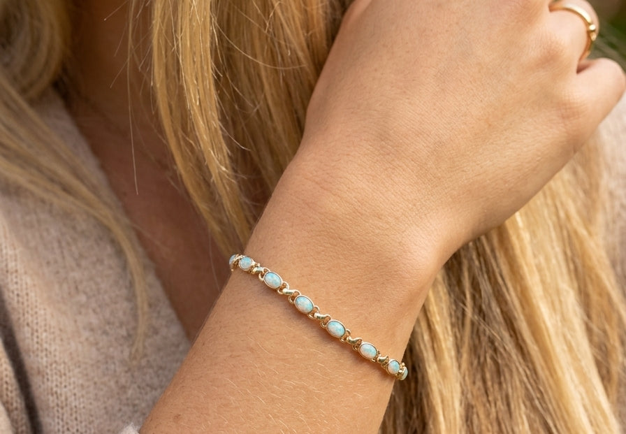 model An elegant line bracelet set with fourteen oval opals, each measuring approximately 5 x 3 mm, displaying a pleasing and lively play of colour.