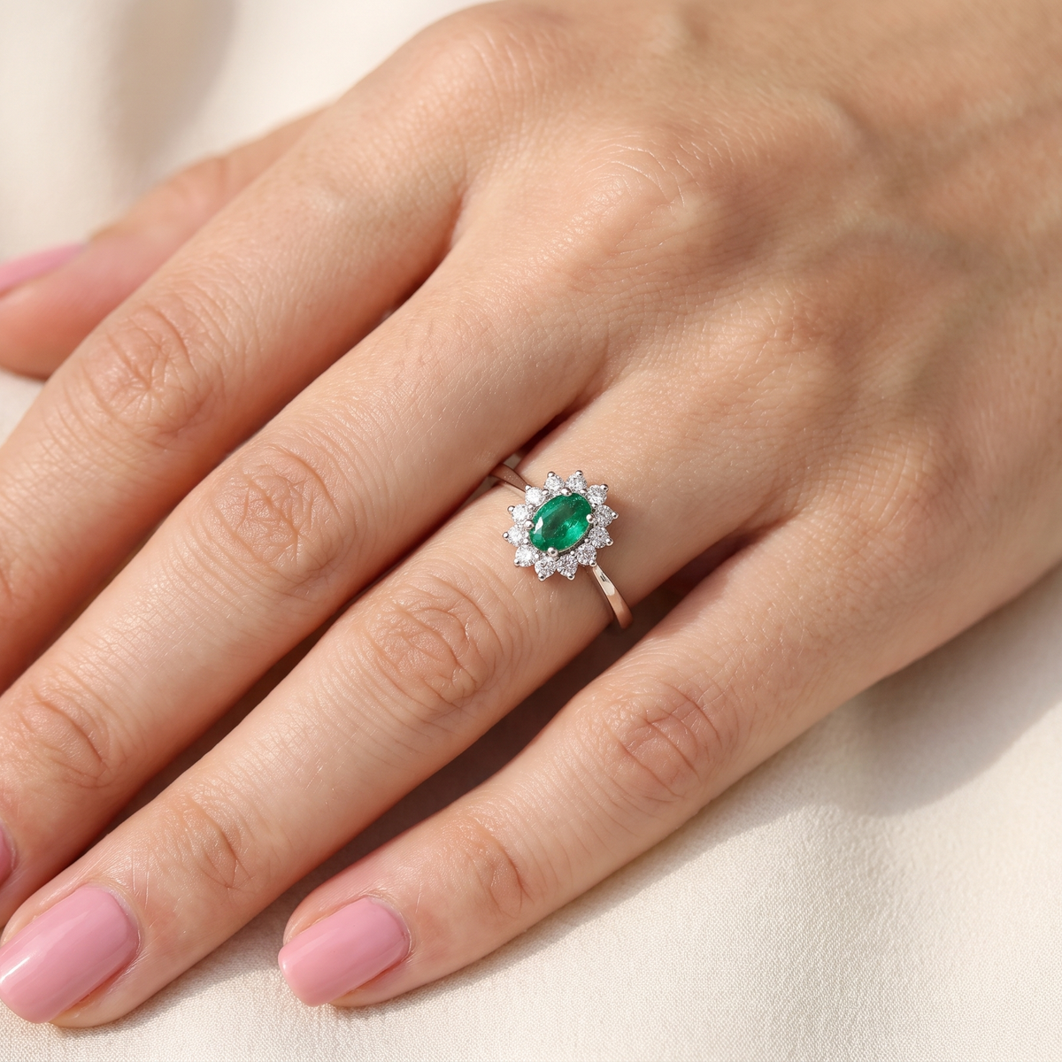 model white gold cluster ring.
Centre stone is an oval cut emerald, 6x3.7mm (just under 0.50 carats) good deep green hue.