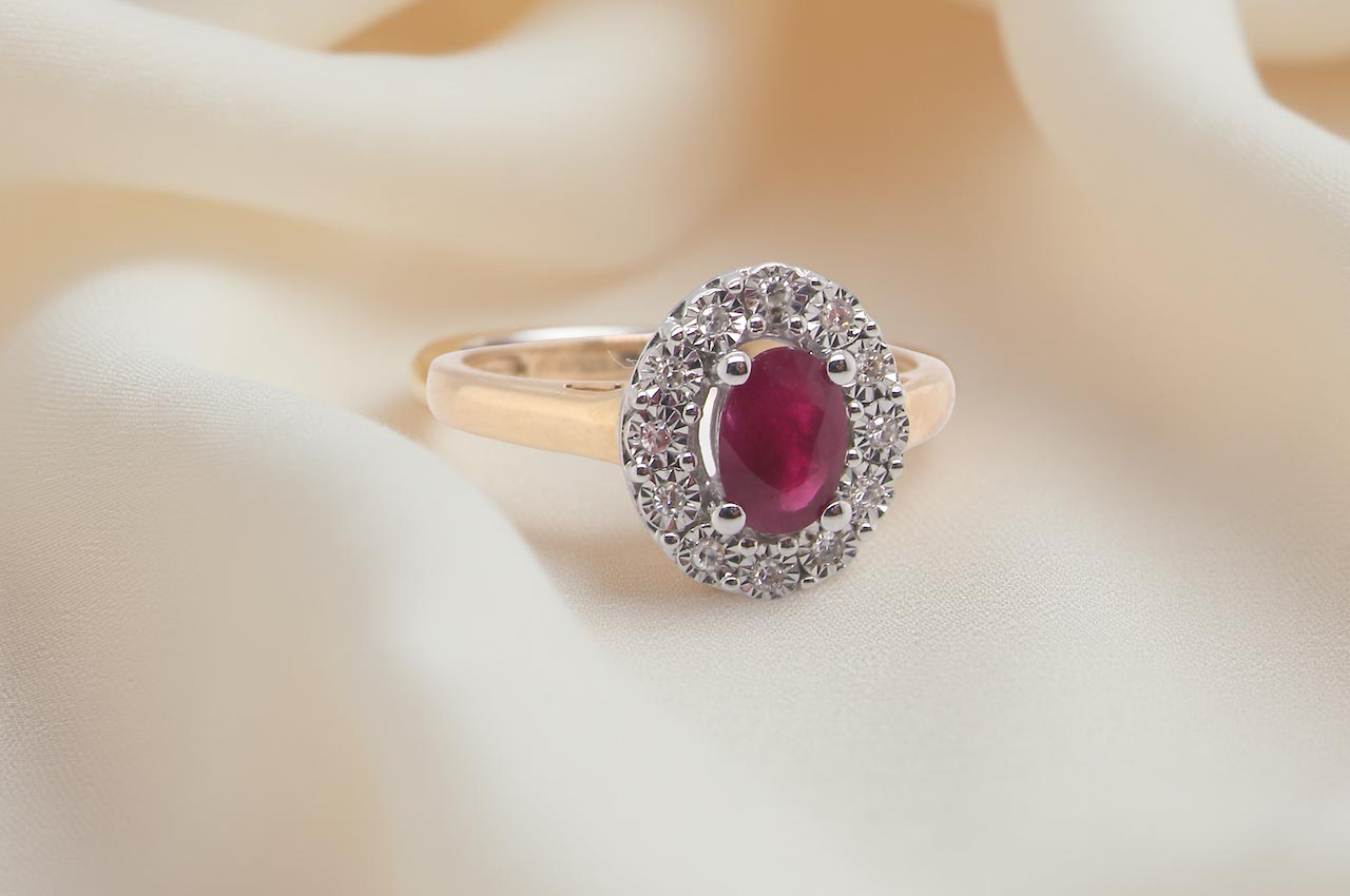 oval ruby measuring 6x4mm (approx. 0.44 carats) in a raspberry red hue. The centre stone is accented by a twelve white diamonds