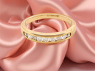 Gold ring with diamonds on a pink satin background