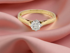 Gold ring with a diamond on a pink fabric background