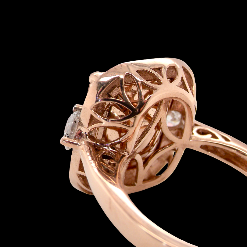 Rose gold filigree ring with a diamond cluster setting, shown in a close-up side profile against a solid black background.