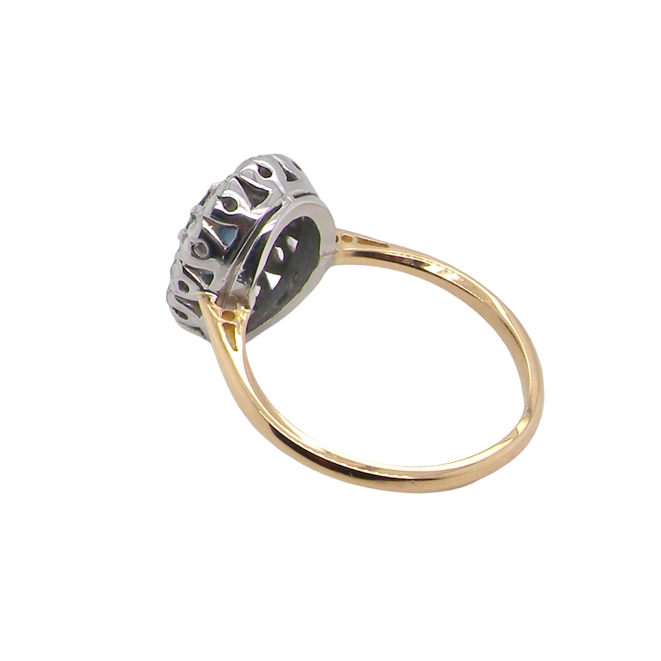 A vintage cluster ring featuring an oval mid-blue sapphire