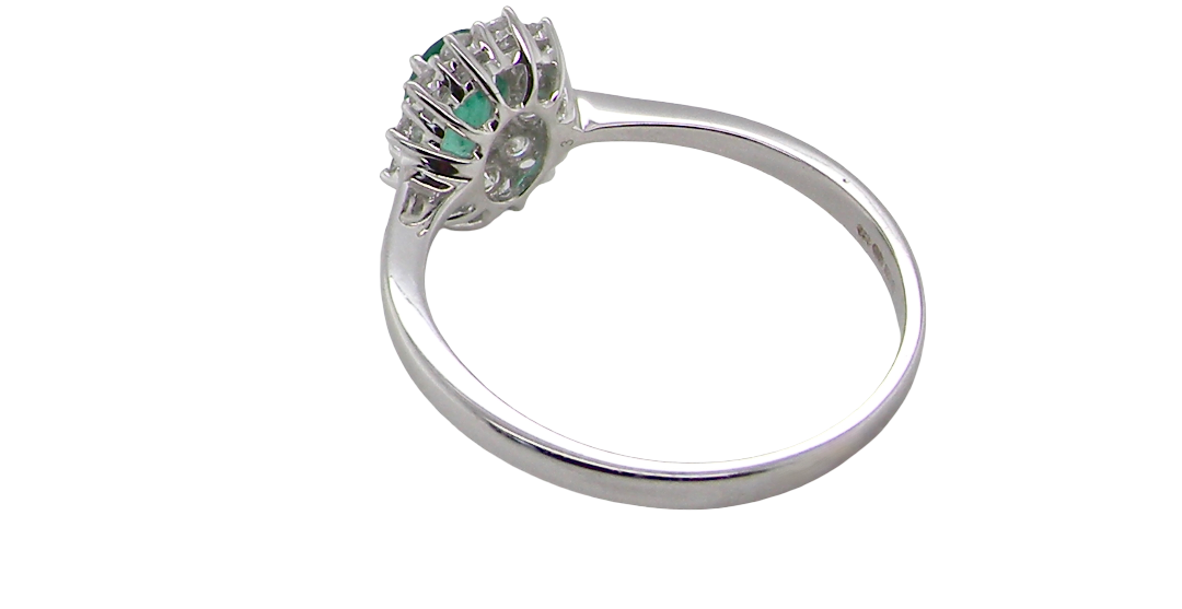 rear A classic cluster ring set with an oval cut emerald centre stone, measures 6x4mm, grass green colour.
Complimented by an outer halo of twelve brilliant cut white diamonds, each 1.7mm (total est at 0.25 carats)