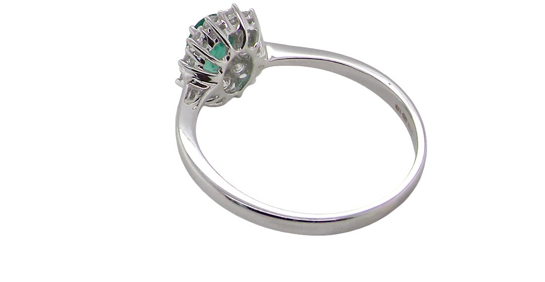 rear A classic cluster ring set with an oval cut emerald centre stone, measures 6x4mm, grass green colour.
Complimented by an outer halo of twelve brilliant cut white diamonds, each 1.7mm (total est at 0.25 carats)