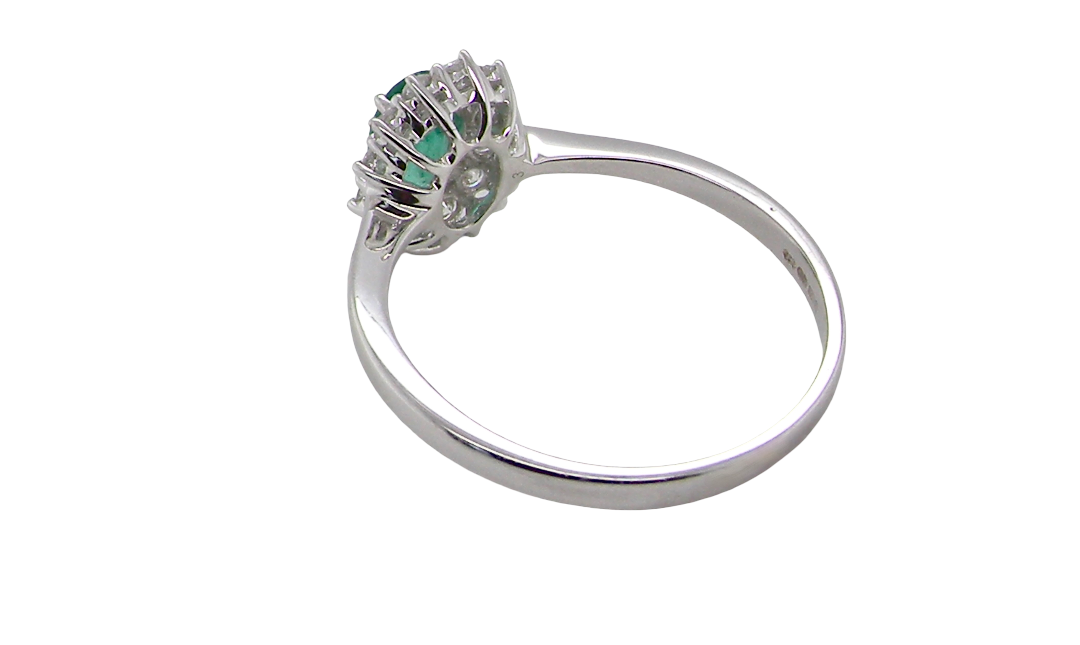 rear A classic cluster ring set with an oval cut emerald centre stone, measures 6x4mm, grass green colour.
Complimented by an outer halo of twelve brilliant cut white diamonds, each 1.7mm (total est at 0.25 carats)