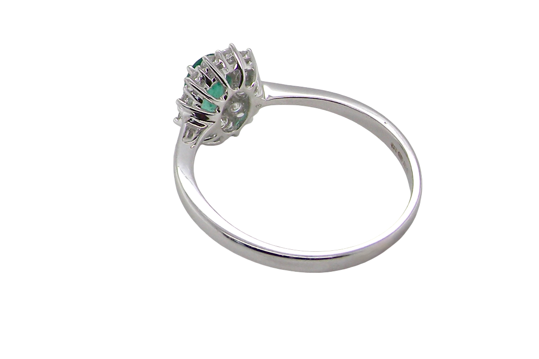 rear A classic cluster ring set with an oval cut emerald centre stone, measures 6x4mm, grass green colour.
Complimented by an outer halo of twelve brilliant cut white diamonds, each 1.7mm (total est at 0.25 carats)