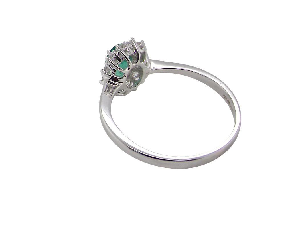 rear A classic cluster ring set with an oval cut emerald centre stone, measures 6x4mm, grass green colour.
Complimented by an outer halo of twelve brilliant cut white diamonds, each 1.7mm (total est at 0.25 carats)