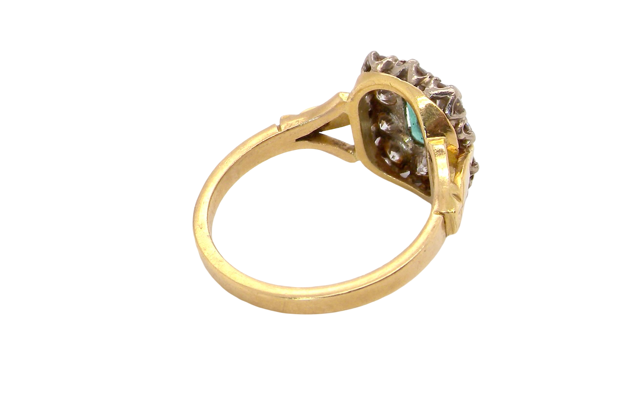 rear A cluster ring that features a rectangular emerald centre stone, 7x5mm . Deep green colour, natural inclusions that can be seen under an eye glass, but not easily visible via the naked eye.
