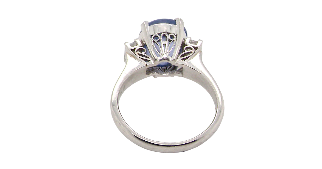rear A fine platinum* ring. Features a lovely sky blue sapphire with 'star sapphire ' chatoyancy , measures 10x9mm, (est 4 carats) held by four claws, cabouchon cut