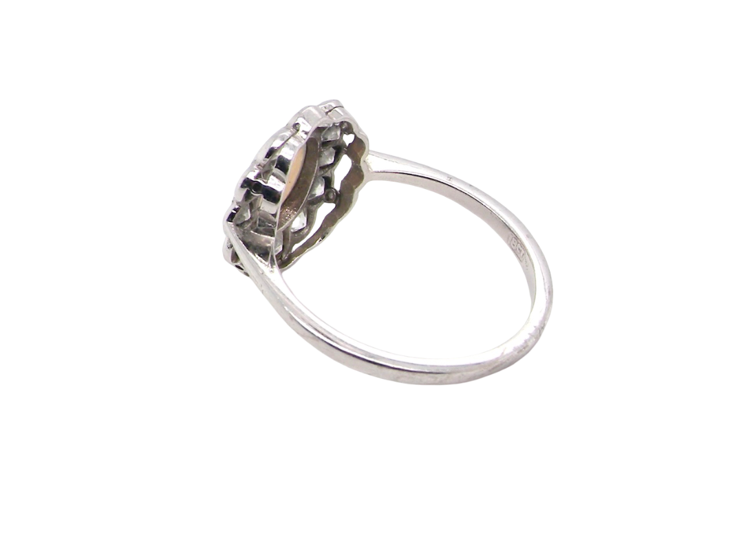 rear A fine vintage cluster ring. Features to the centre an oval shaped opal, with excellent play of colour, pink to one way, vibrant green to the other with flashes of electric blue also within the body of the gem.