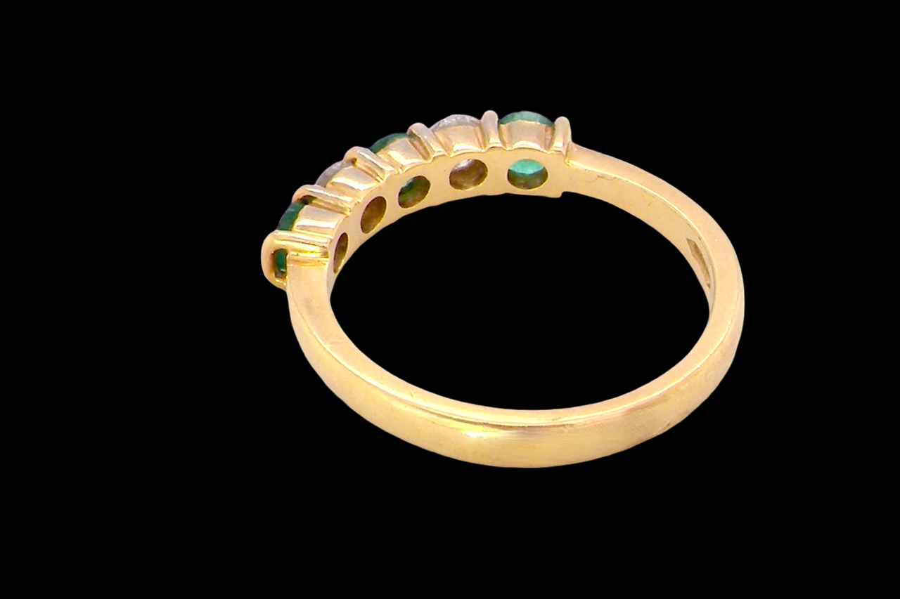 rear A five stone ring set with three emeralds, each 3mm diameter.
Between each two brilliant cut white diamonds, each 3.4mm (0.15 carats each est), colour i-j, clarity Si.