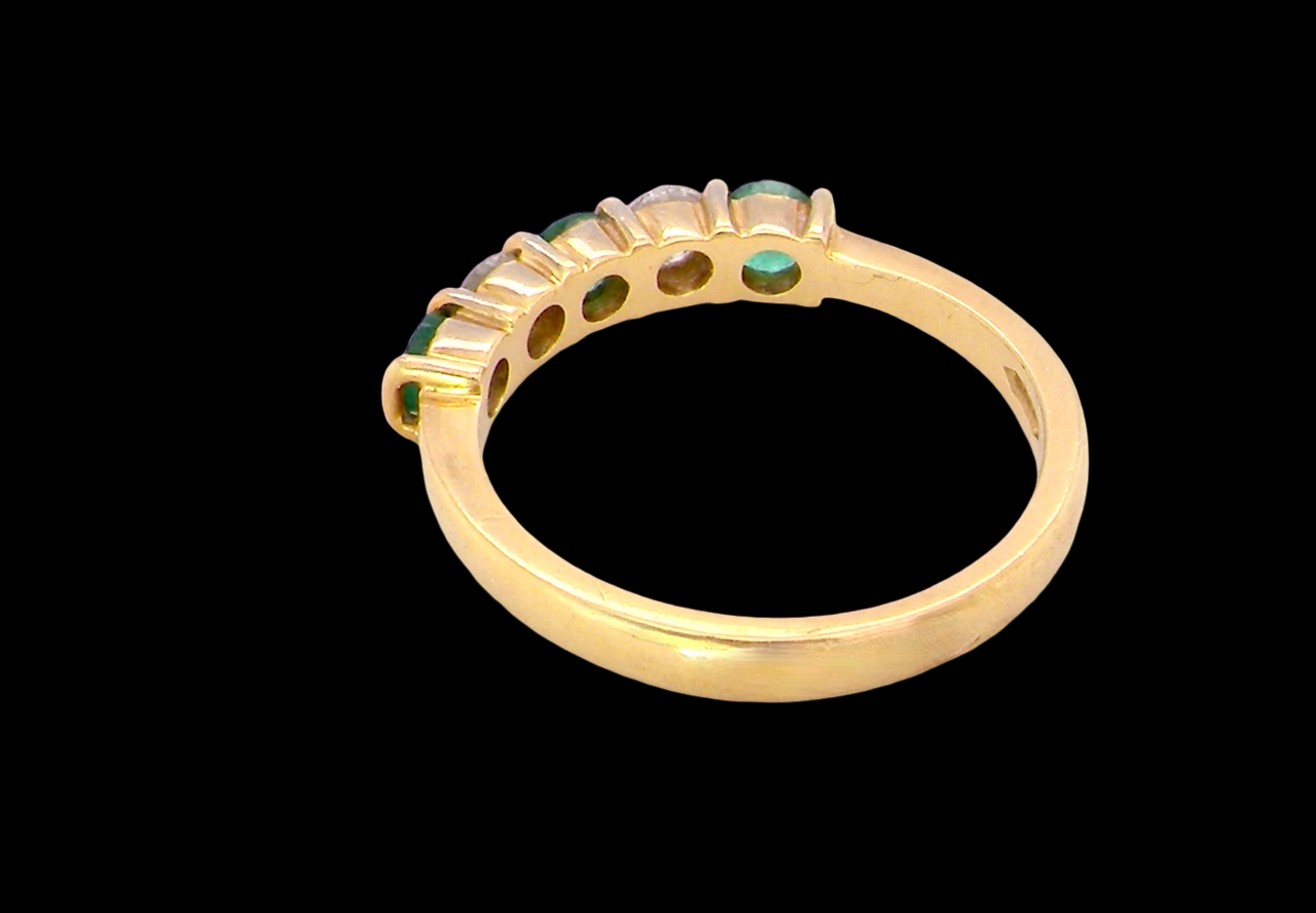 rear A five stone ring set with three emeralds, each 3mm diameter.
Between each two brilliant cut white diamonds, each 3.4mm (0.15 carats each est), colour i-j, clarity Si.