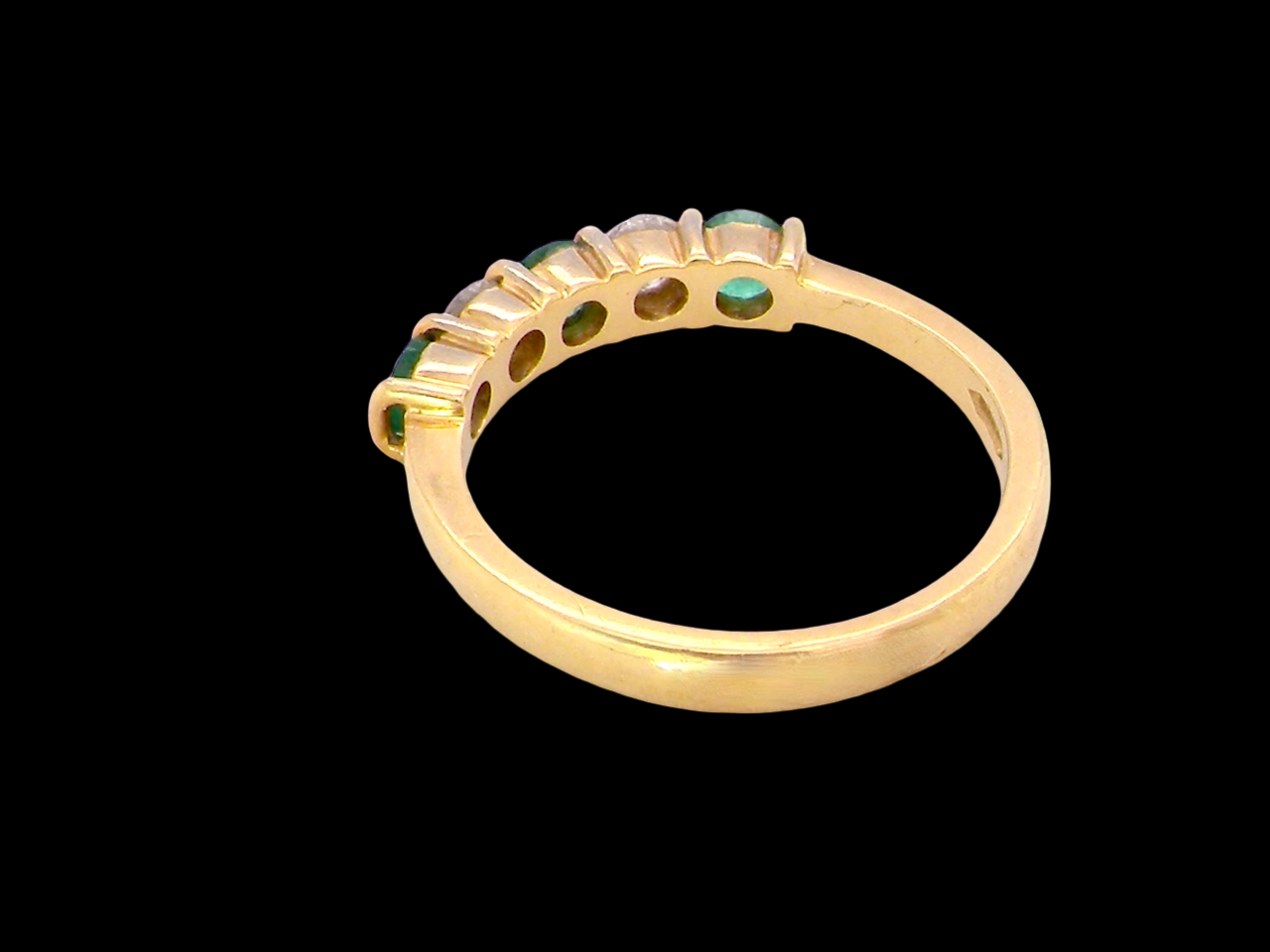 rear A five stone ring set with three emeralds, each 3mm diameter.
Between each two brilliant cut white diamonds, each 3.4mm (0.15 carats each est), colour i-j, clarity Si.