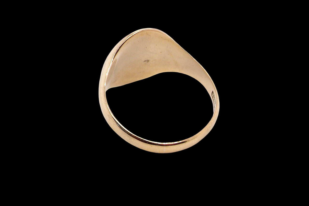 rear A gentlemans 9 carat gold signet ring. The head is oval with a slight pattern to the outer edges. 