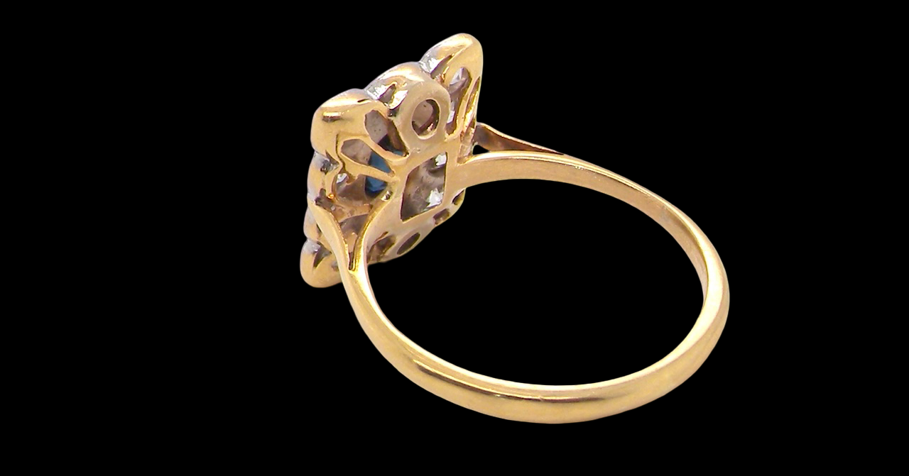 rear A rectangular cluster ring that features in its centre a cushion shaped dark blue sapphire, that measures 5x3.5mm (est 0.30 carats)