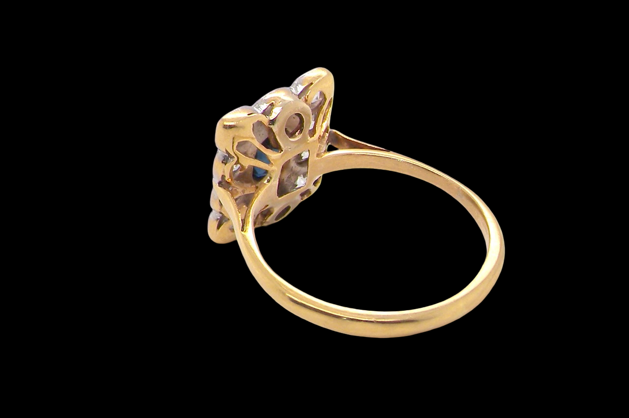 rear A rectangular cluster ring that features in its centre a cushion shaped dark blue sapphire, that measures 5x3.5mm (est 0.30 carats)