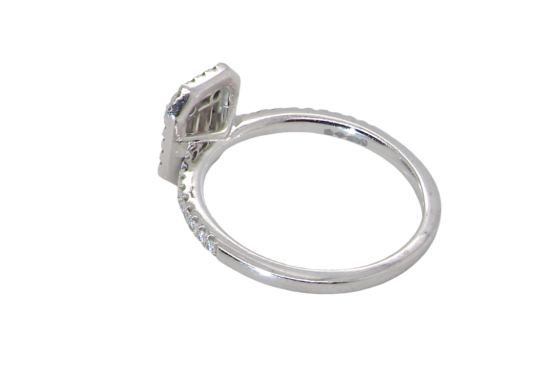 rear A rectangular diamond cluster ring. Centre portion is set with three baguette cut white diamonds 3x1.6mm and six mixed cut diamonds 2mm each.
Surrounded by a halo of twenty two small round diamonds