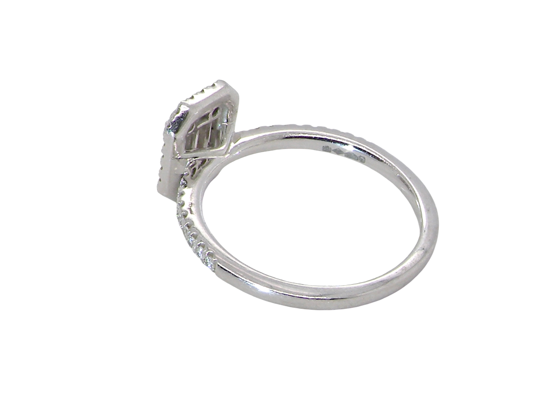rear A rectangular diamond cluster ring. Centre portion is set with three baguette cut white diamonds 3x1.6mm and six mixed cut diamonds 2mm each.
Surrounded by a halo of twenty two small round diamonds