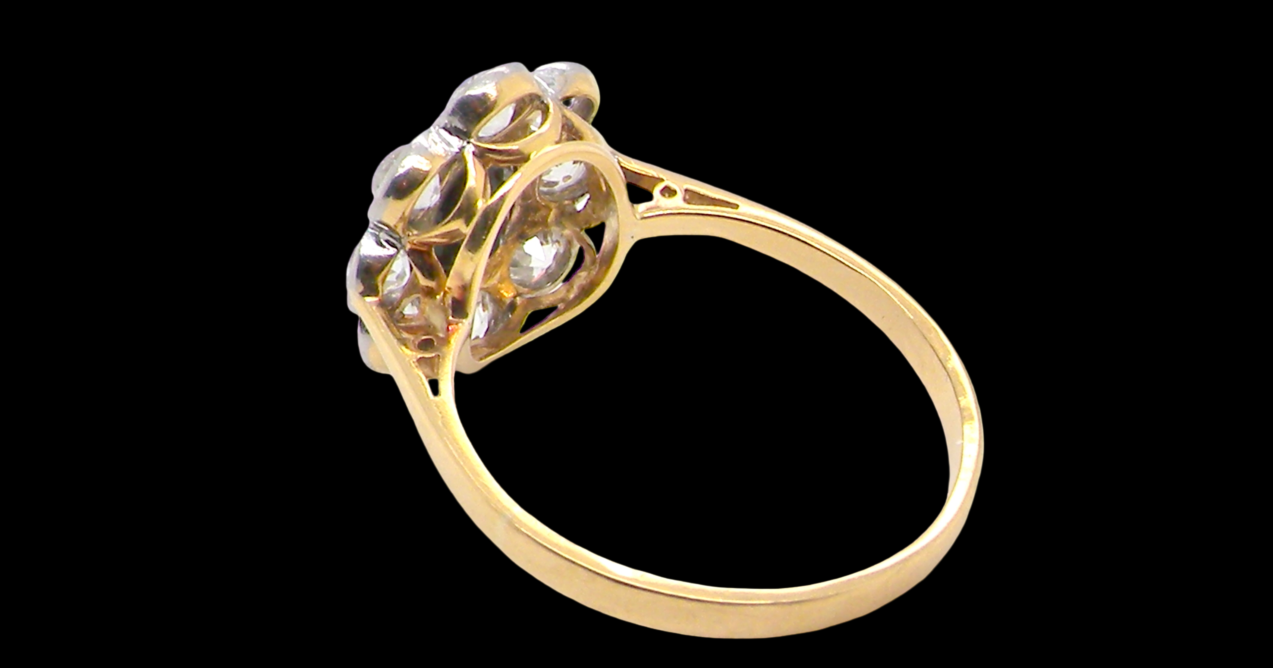 rear A striking vintage sapphire and diamond cluster ring dating from the 1930s–1940s, beautifully crafted in platinum and 18 carat gold. At the centre sits a richly coloured oval-cut sapphire of deep inky blue-black hue, measuring approximately 7 x 5mm and estimated at 0.75 carats.
