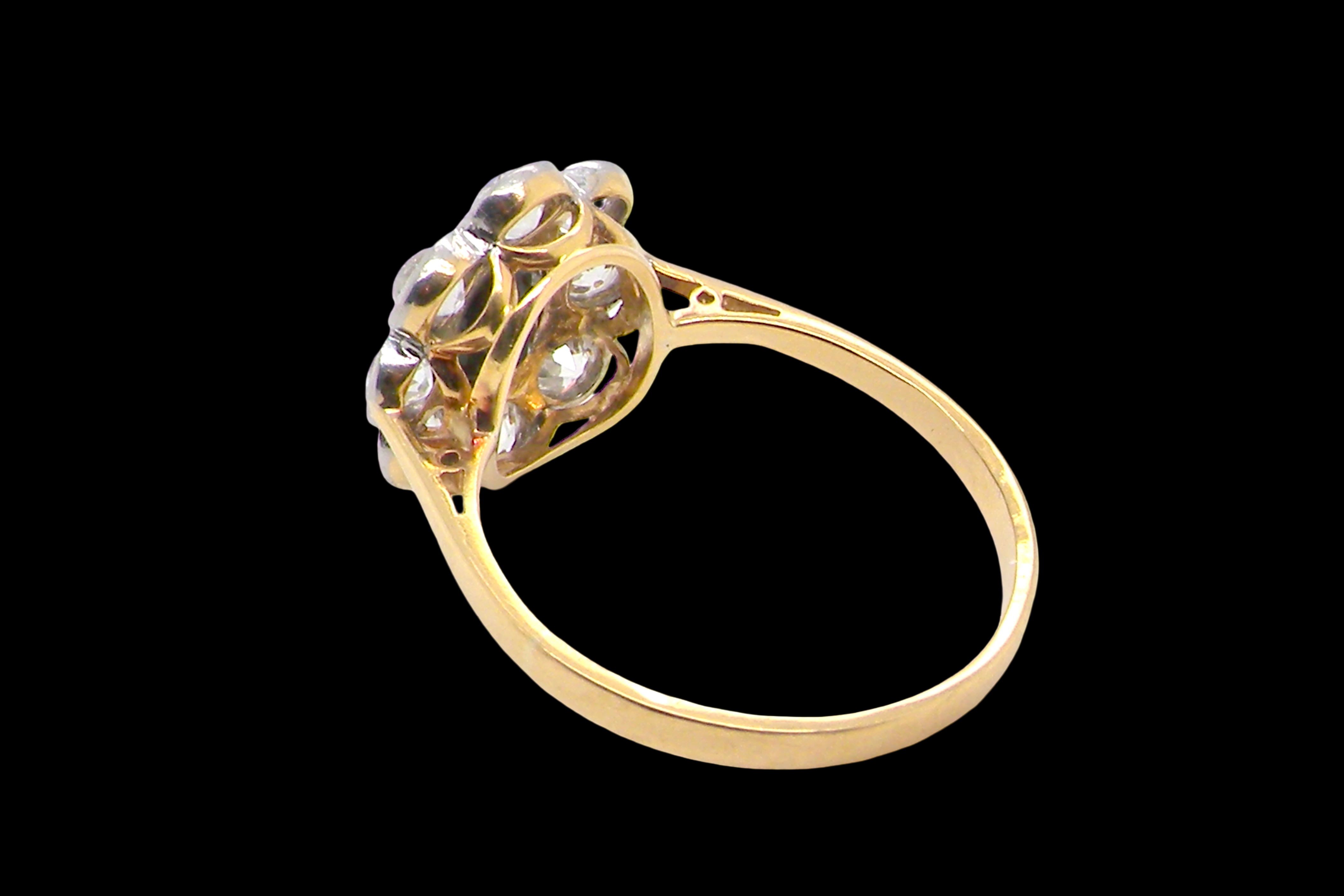 rear A striking vintage sapphire and diamond cluster ring dating from the 1930s–1940s, beautifully crafted in platinum and 18 carat gold. At the centre sits a richly coloured oval-cut sapphire of deep inky blue-black hue, measuring approximately 7 x 5mm and estimated at 0.75 carats.