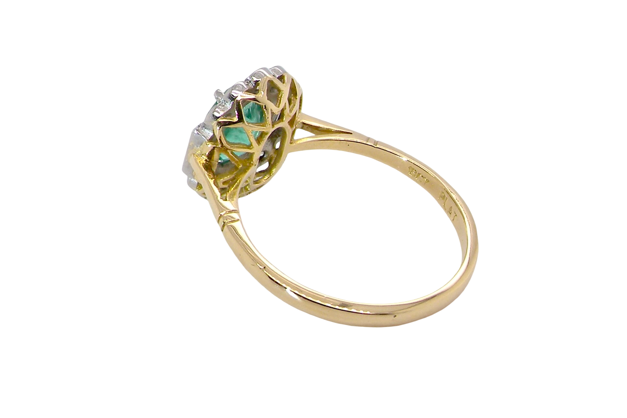 rear A stunning vintage cluster ring, set with an oval-cut emerald measuring 8 x 6mm, approximately 1.10 carats. The emerald displays a rich, deep grass-green colour with natural inclusions, typical of a genuine stone.