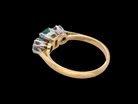 Gold ring with emerald and diamond-like stones on a black background