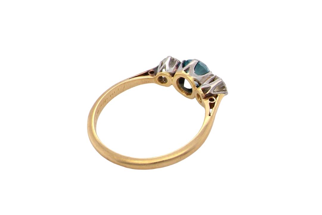 rear A vintage three stone ring. Centre stone, a round 5.8mm natural blue zircon.
To each side an old brilliant cut white diamond 4mm round (est 0.25 carats). Colour i-j, clarity Si.