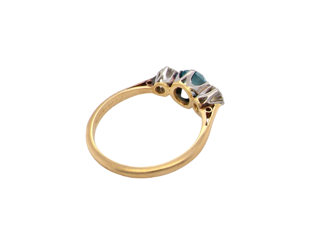 rear A vintage three stone ring. Centre stone, a round 5.8mm natural blue zircon.
To each side an old brilliant cut white diamond 4mm round (est 0.25 carats). Colour i-j, clarity Si.
