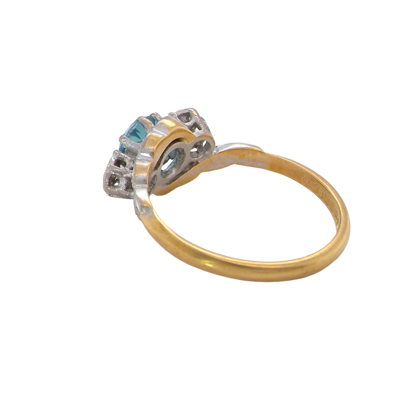rear A vintage three stone ring, cross over style and features a round 6mm natural blue zircon centre stone