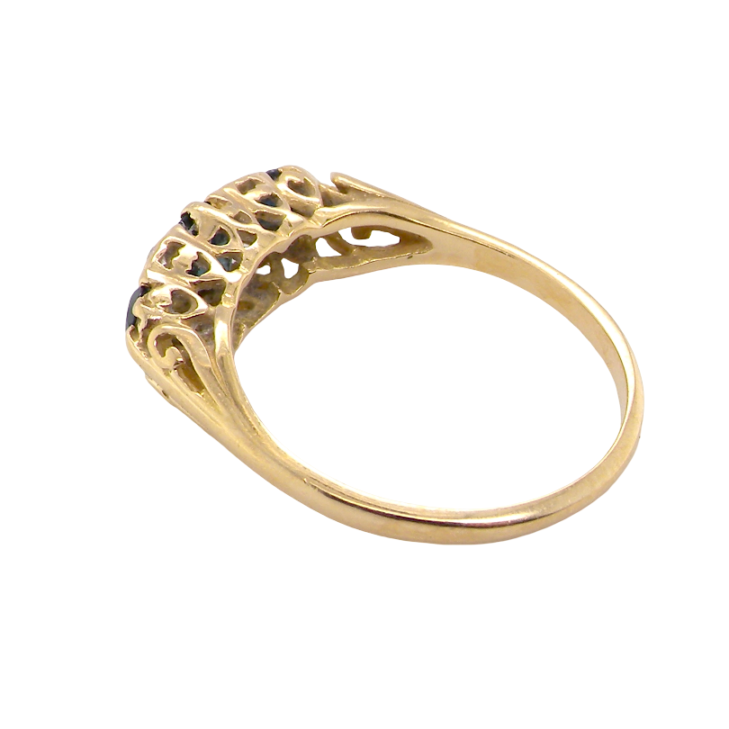 A yellow gold ring with an intricate filigree crown featuring small dark blue gemstones, shown on a plain white background.