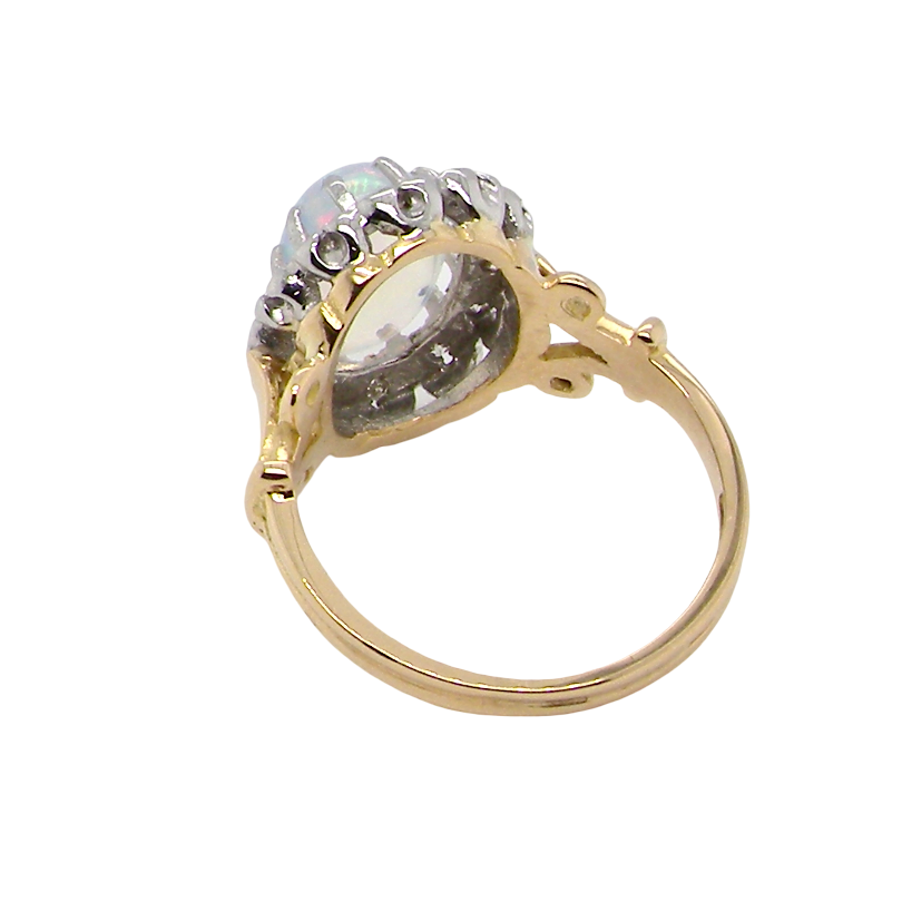 rear An 18 carat gold cluster ring. Features an oval opal centre stone with excellent play of colour with a predominance of watery purple and flashes of orange, and luminous green.
Measures 11x7mm.