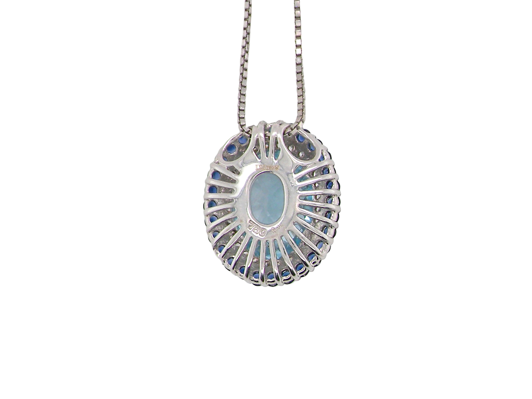 rear An 18 carat white gold oval shaped pendant. Features an oval cut blue topaz centre stone, 13x9mm.
Complimented by an outer halo of approximately thirty small brilliant cut white diamonds,