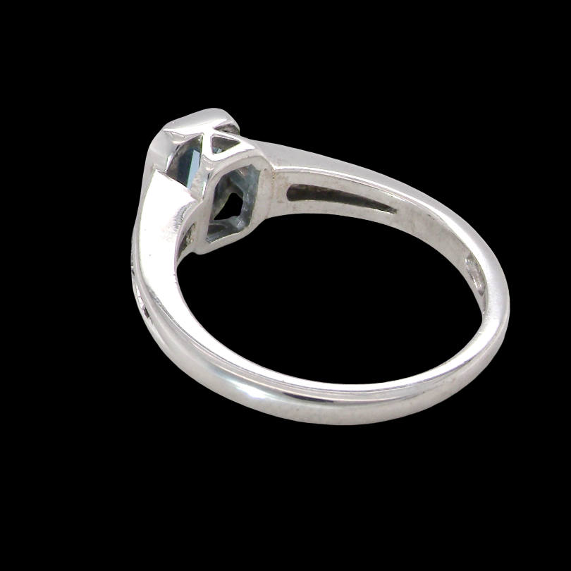rear An 18 carat white gold ring, features a rectangular step cut aquamarine, measures 7x5mm (st one carat) sky blue, fine clarity. Rim setting.