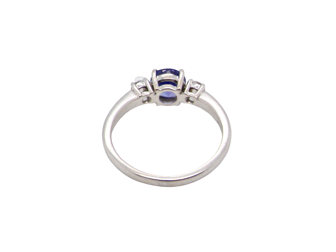 rear An 18 carat white gold three stone ring. Centre stone a round tanzanite 6mm diameter.
Each side a brilliant cut white diamond