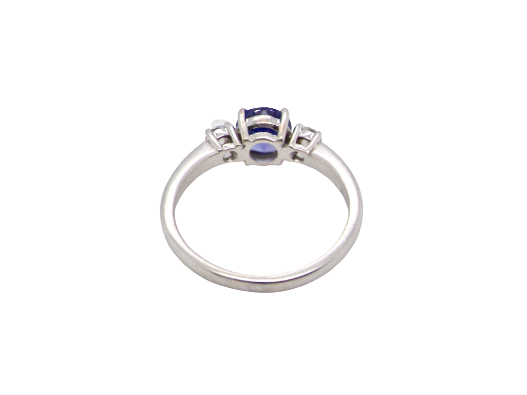 rear An 18 carat white gold three stone ring. Centre stone a round tanzanite 6mm diameter.
Each side a brilliant cut white diamond
