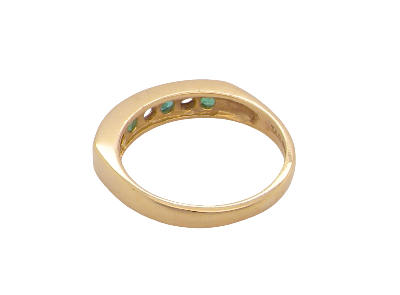 rear An 18 carat yellow gold half hoop eternity ring. Set with four round emeralds, each 3mm, and alternate set with brilliant cut white diamonds, each 3mm (total est 0.30 carats)