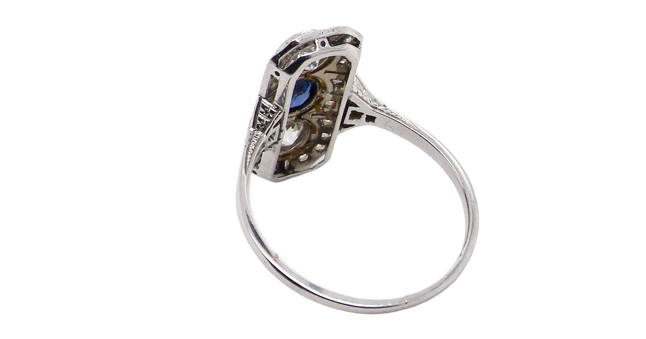 rear The plaque design has at its centre a mid to dark blue sapphire, 5x4mm (est 0.40 carats) mille grain set. Above and below to Old European Cut white diamonds. Each one estimated at 0.40 carats (4.8mm) Colour H-j, clarity Si.