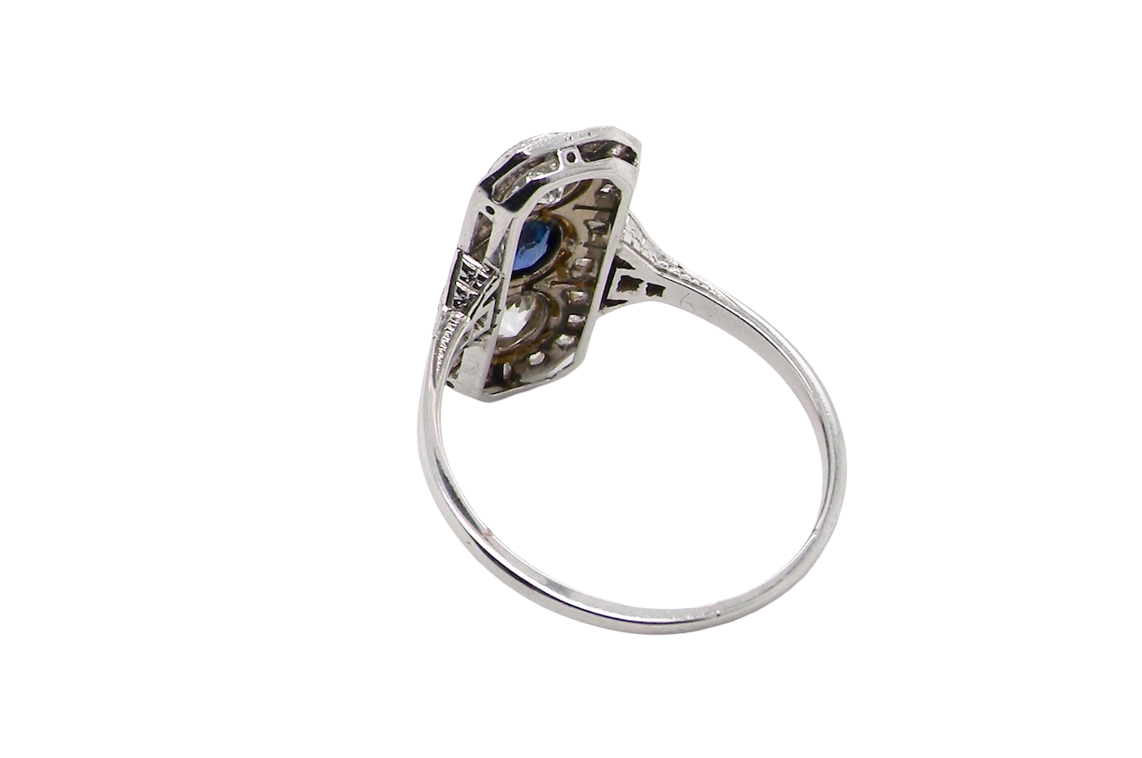rear The plaque design has at its centre a mid to dark blue sapphire, 5x4mm (est 0.40 carats) mille grain set. Above and below to Old European Cut white diamonds. Each one estimated at 0.40 carats (4.8mm) Colour H-j, clarity Si.