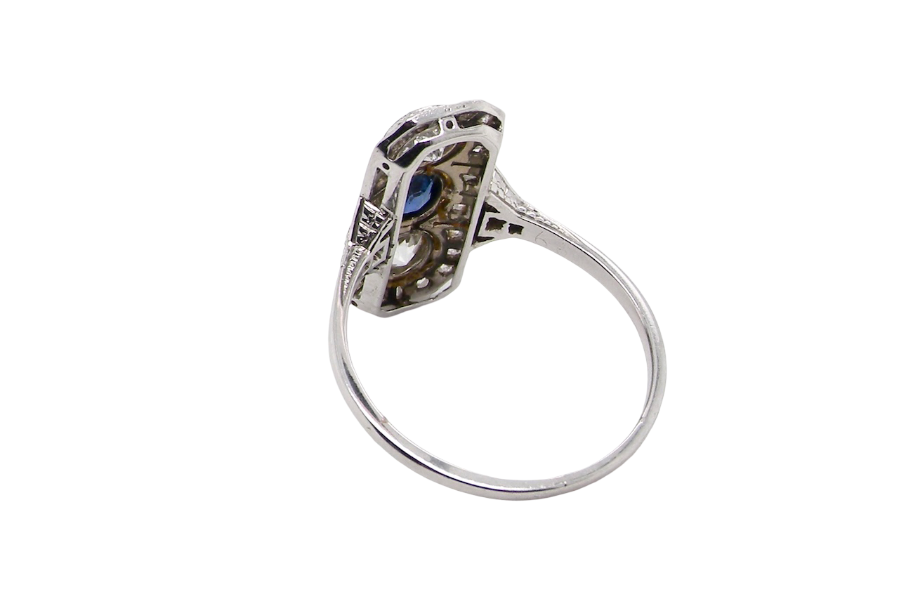 rear The plaque design has at its centre a mid to dark blue sapphire, 5x4mm (est 0.40 carats) mille grain set. Above and below to Old European Cut white diamonds. Each one estimated at 0.40 carats (4.8mm) Colour H-j, clarity Si.