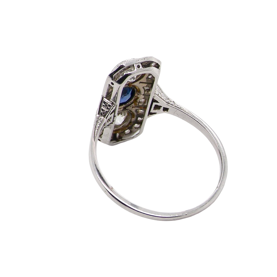 rear The plaque design has at its centre a mid to dark blue sapphire, 5x4mm (est 0.40 carats) mille grain set. Above and below to Old European Cut white diamonds. Each one estimated at 0.40 carats (4.8mm) Colour H-j, clarity Si.