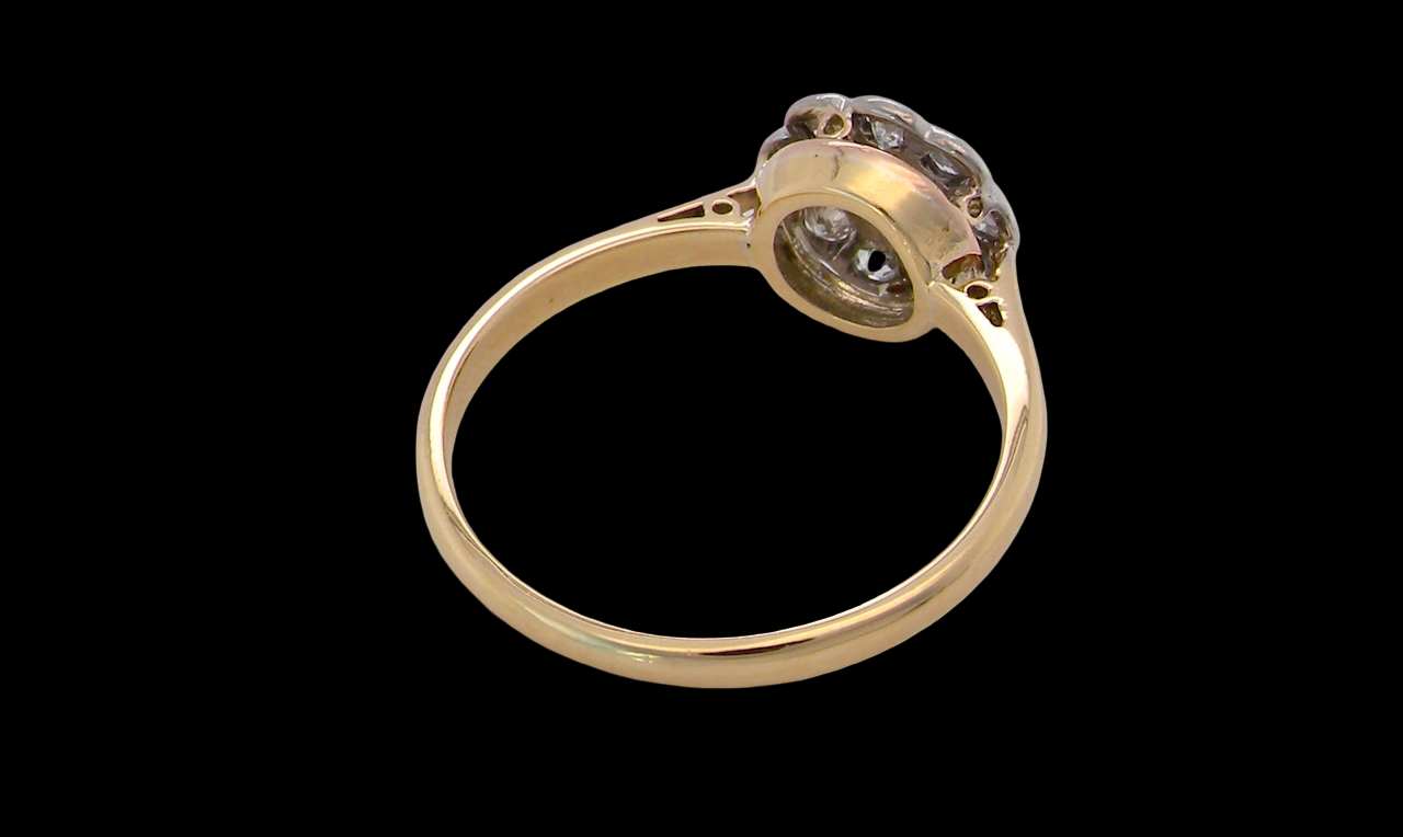 rear early 20th-century vintage diamond cluster ring, featuring a classic daisy-shaped head set with nine old brilliant-cut white diamonds.