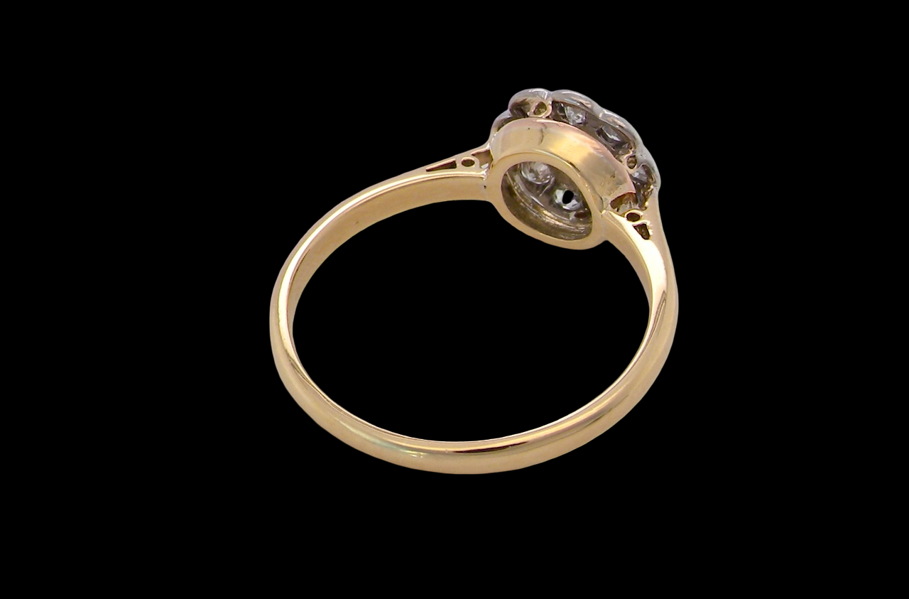 rear early 20th-century vintage diamond cluster ring, featuring a classic daisy-shaped head set with nine old brilliant-cut white diamonds.