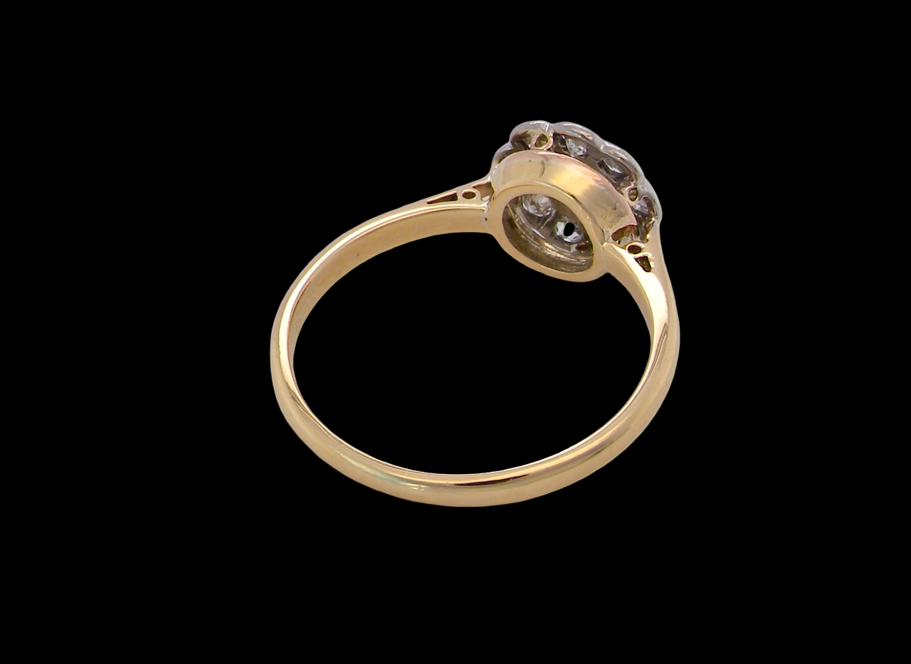 rear early 20th-century vintage diamond cluster ring, featuring a classic daisy-shaped head set with nine old brilliant-cut white diamonds.