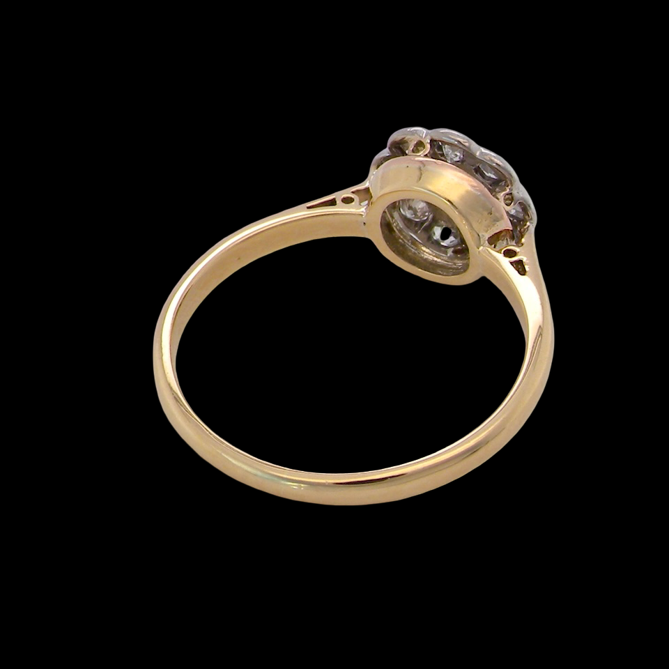 rear early 20th-century vintage diamond cluster ring, featuring a classic daisy-shaped head set with nine old brilliant-cut white diamonds.