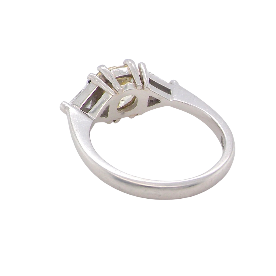 rear striking and elegant trilogy ring crafted in 18-carat white gold, set with a vibrant fancy yellow cushion-cut diamond