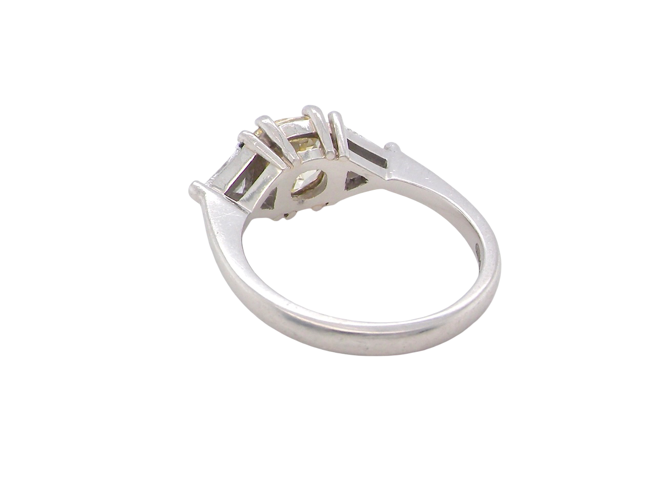 rear striking and elegant trilogy ring crafted in 18-carat white gold, set with a vibrant fancy yellow cushion-cut diamond