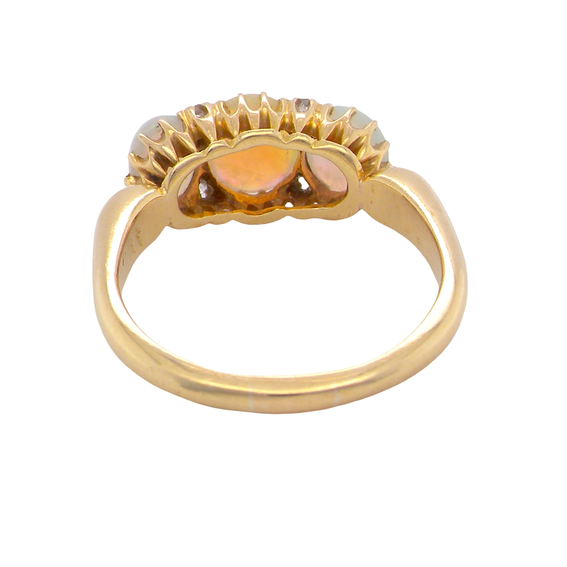 A vintage gold ring with a scalloped top setting featuring three amber-orange heart-shaped stones, shown on a plain white background.