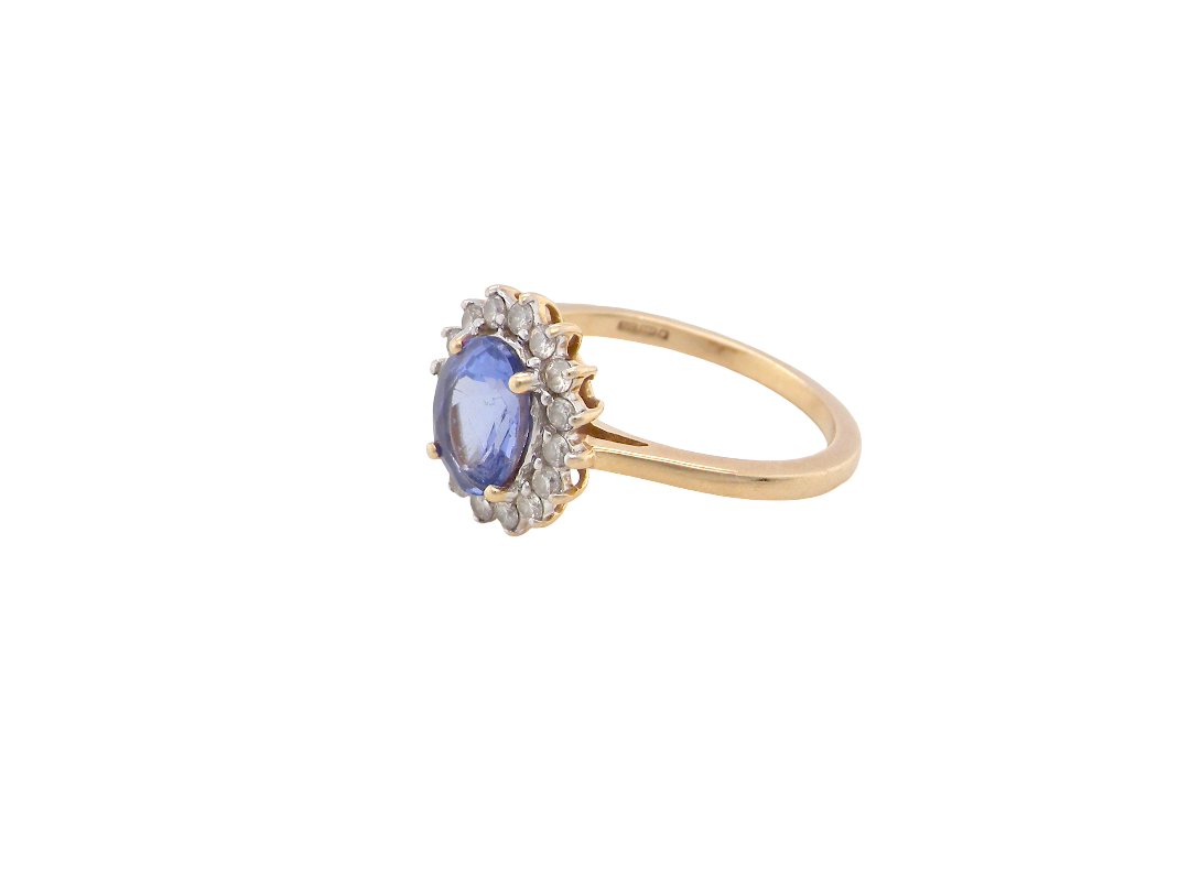 side A 14 carat gold cluster ring. Features to the centre an oval cut cornflower blue sapphire, 8x6mm (est 1.25 carats), four claw setting.