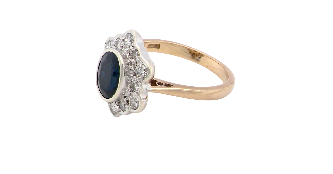 side A 9 carat gold cluster ring that features an inky black blue oval cut sapphire. This measures 8x6mm in a safe rim style setting